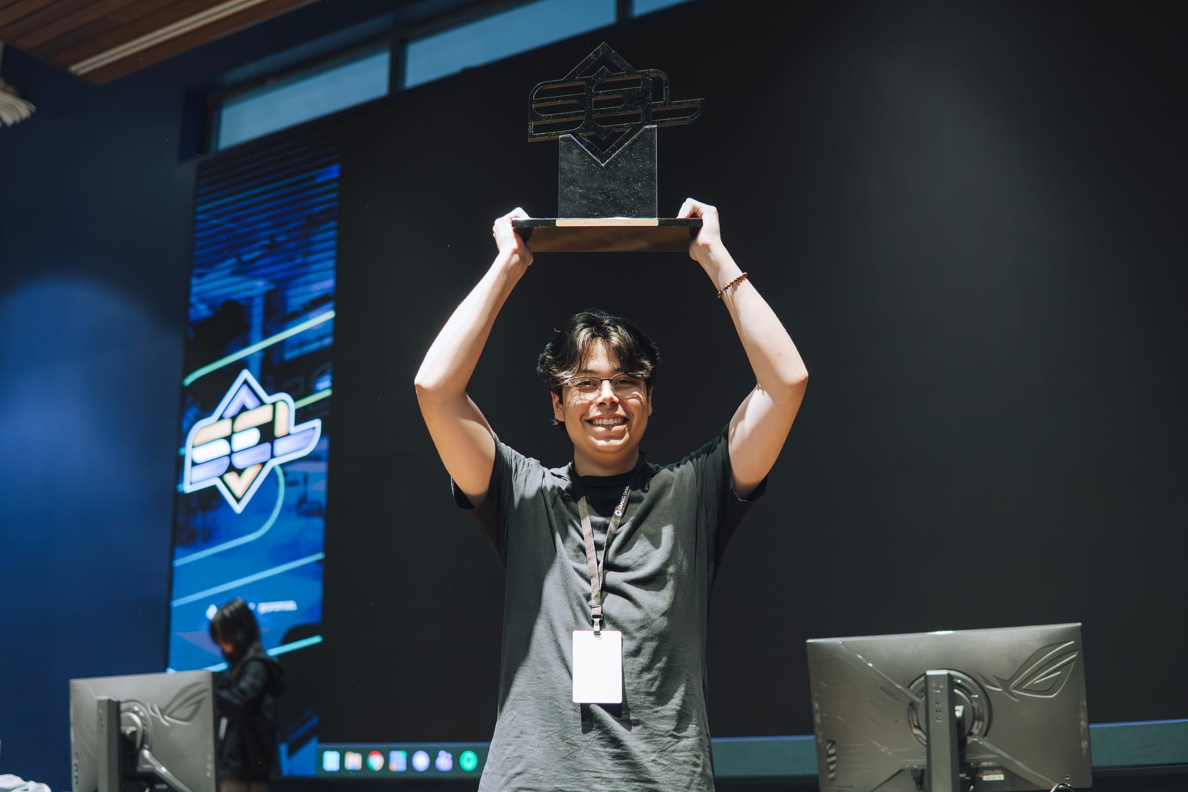 SEL competitor celebrates with a championship trophy on stage